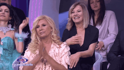 a group of women sitting in front of a screen that says grandefratello