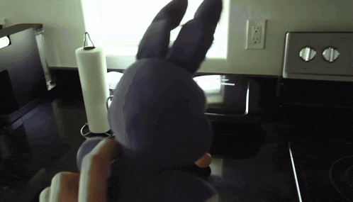 a purple stuffed bunny is sitting on a kitchen counter