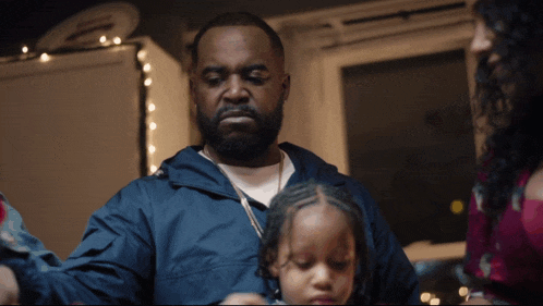 a man in a blue jacket is holding a little girl