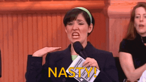 a woman holds a microphone and says nasty in yellow letters