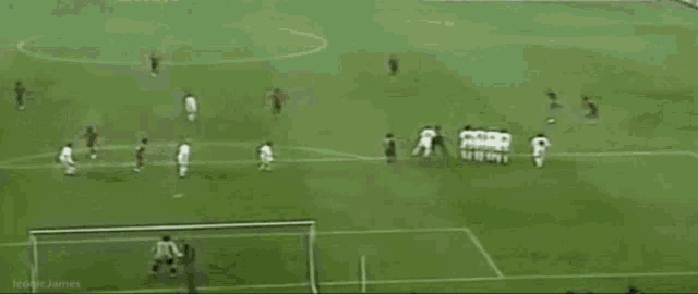 a soccer player is laying on the ground in front of a goal while a soccer ball is in the air .