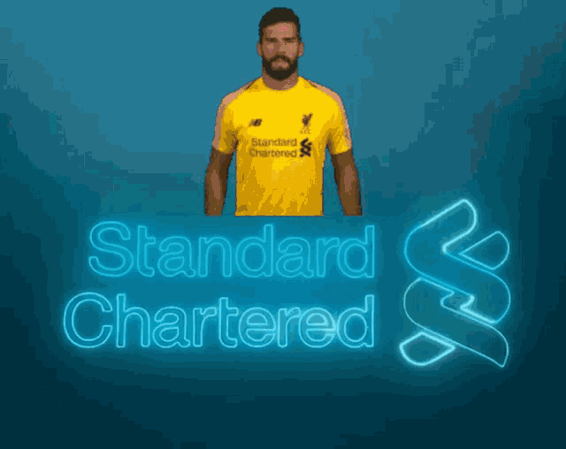 a man in a yellow standard chartered jersey stands in front of a blue background