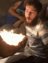 a man with a beard is sitting at a table with candles on it .