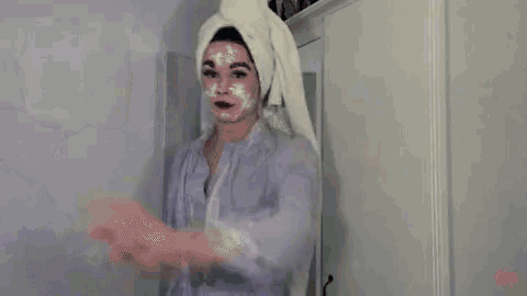 a person is standing in a closet holding a towel and a blanket .