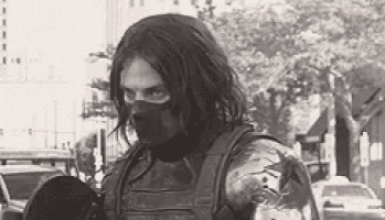 a black and white photo of a man in a superhero costume holding a skateboard .
