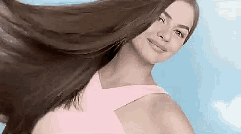 a woman in a pink dress is holding her hair in the air and smiling .