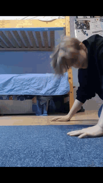 a person doing push ups on a blue carpet in front of a bunk bed