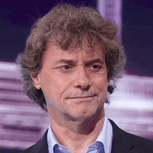 a man with curly hair is wearing a blue shirt and a black jacket