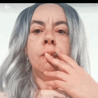 a woman with blue hair is smoking a cigarette with an arrow pointing to the left