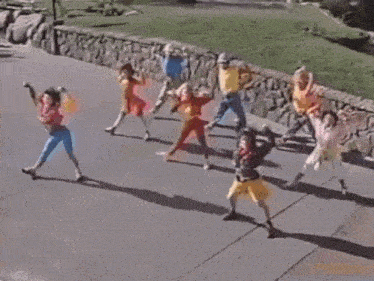 a group of young people are dancing on a sidewalk .