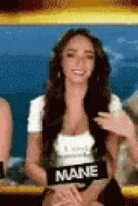 a woman with long hair is sitting in front of a sign that says mane on it .