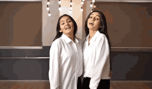 two women in white shirts stand next to each other