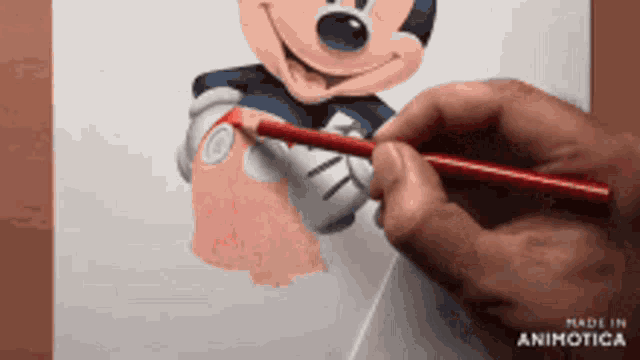 a person is drawing a picture of mickey mouse on a piece of paper