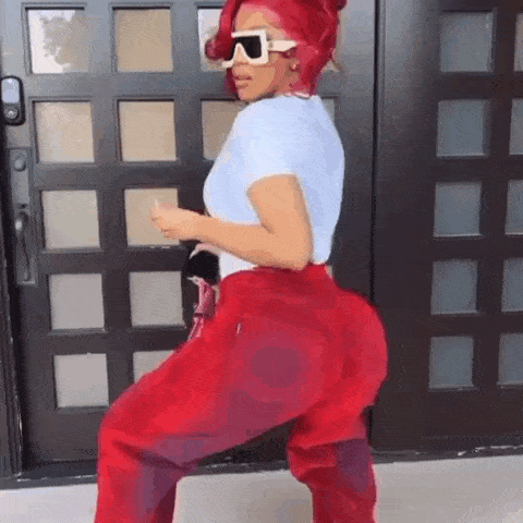 a woman with red hair and sunglasses is standing in front of a door .