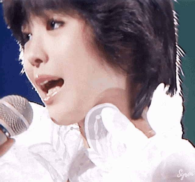 a close up of a woman singing into a microphone with the name syrena on the bottom right