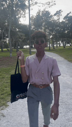 a man in a pink shirt is holding a black bag that says create on it