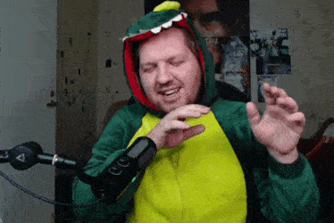 a man in a dinosaur costume stands in front of a microphone with the letter a on it