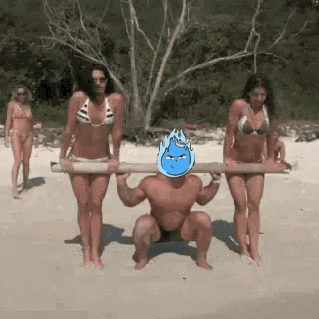 a man squatting on the beach with two women holding a wooden plank over his head