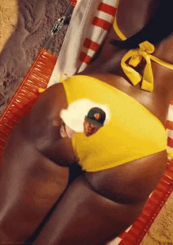 a woman in a yellow bikini is laying on a beach