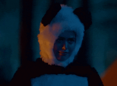 a woman in a panda costume is standing in the dark .