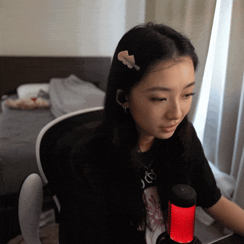 a woman sitting in front of a microphone wearing a black shirt that says jc
