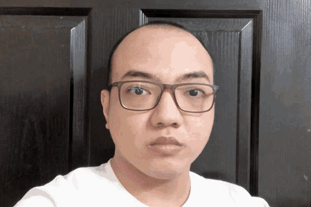 a bald man wearing glasses looks at the camera