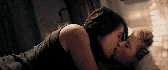 a man and a woman are kissing each other in bed .