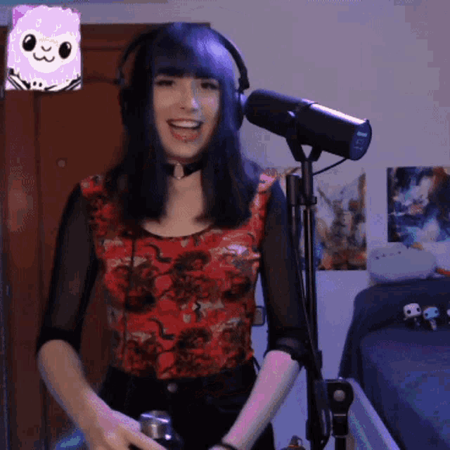 a woman wearing headphones and a choker is smiling in front of a microphone