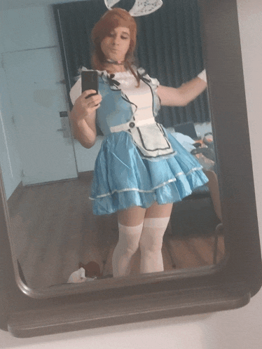 a woman in a blue dress taking a selfie in a mirror