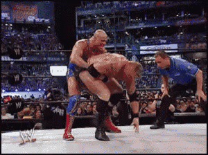 two wrestlers are wrestling in a ring with a referee and a crowd watching