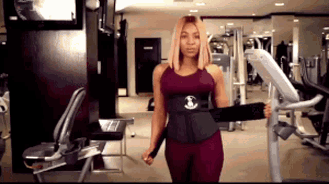 a woman is standing in a gym wearing a black waist trainer