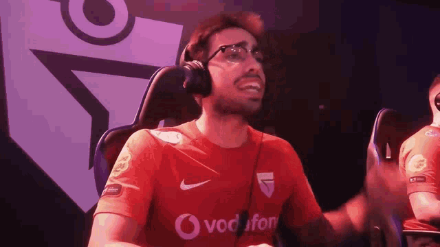 a man wearing headphones and a red shirt with the word vodafone on it