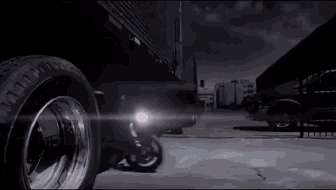 a truck is driving down a parking lot at night with a motorcycle parked next to it .