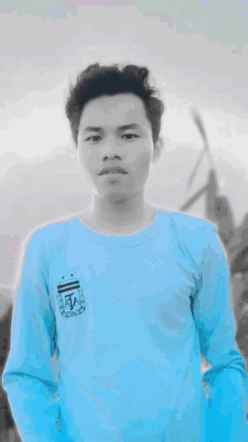a man is wearing a pink shirt and standing in front of a windmill .