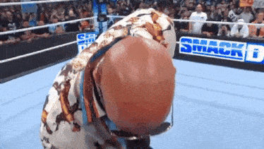 a wrestler is kneeling down in front of a smack down sign