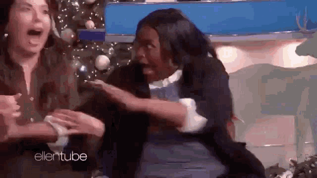 a group of women are sitting in front of a christmas tree on a show .
