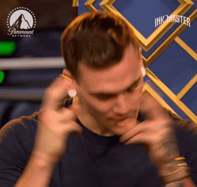 a man is wearing ear plugs in front of a paramount network sign