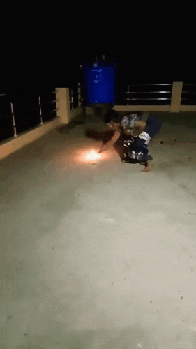 a person laying on a concrete surface with a blue barrel in the background