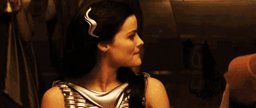 a woman with long black hair is wearing a silver top and a headband .