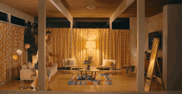 a man is standing in a living room with a mirror