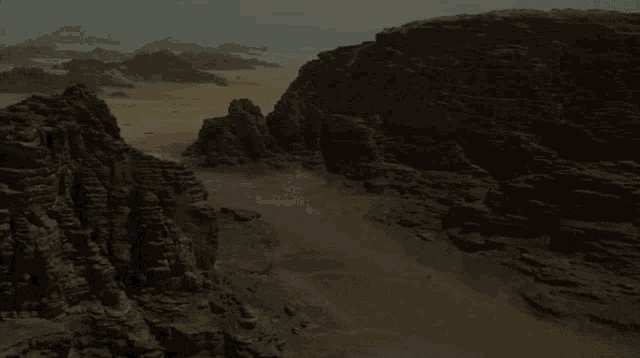 a desert landscape with mountains in the background and a few rocks in the foreground