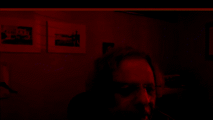a dark room with a few pictures on the wall and a person wearing sunglasses