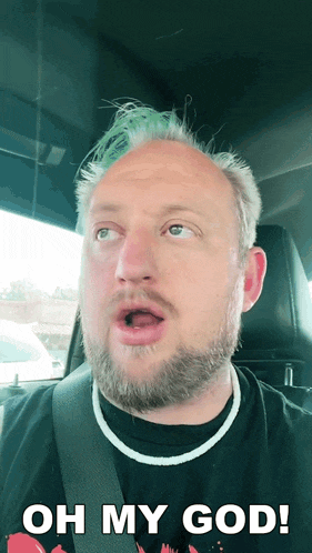 a man with a beard and green hair is sitting in a car and says oh my god