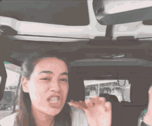 a woman is making a funny face while sitting in the back seat of a car