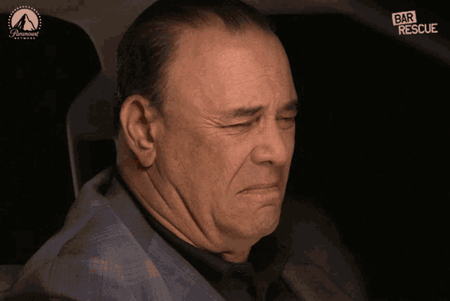 a man is sitting in a car with a paramount logo on the bottom