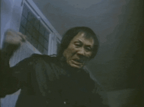 a man is making a funny face in a dark room while holding a knife .