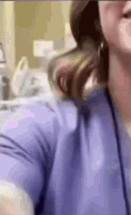 a woman in a purple shirt is taking a selfie in a hospital .