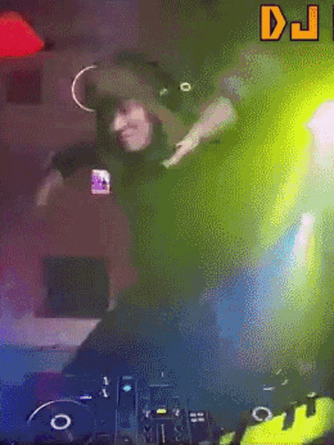 a woman wearing headphones is dancing in front of a dj console
