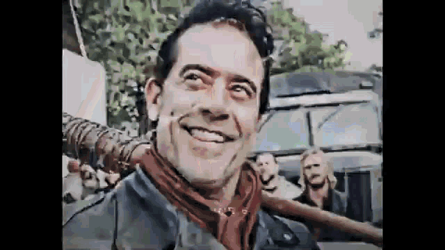 a man in a leather jacket and scarf is smiling and holding a bat .