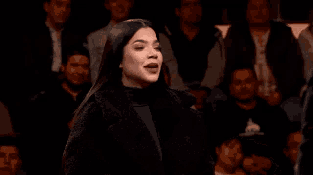 a woman in a black sweater is pointing at something in a crowd